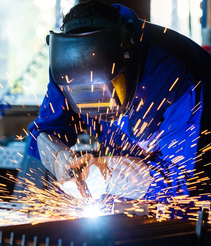 welder welding metal in workshop with sparks